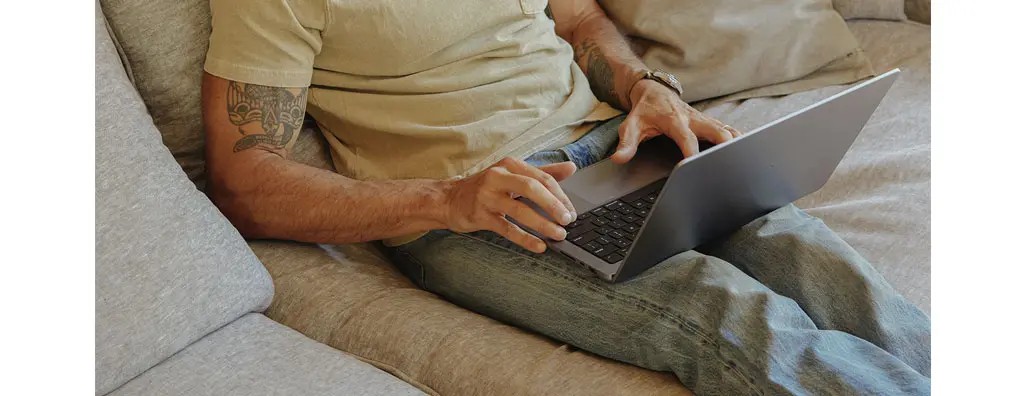 Man working on laptop on a sofa